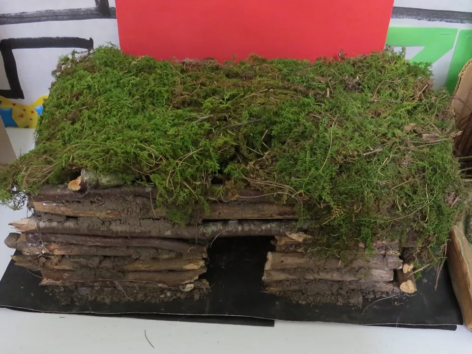 Student model of a log house with a moss roof