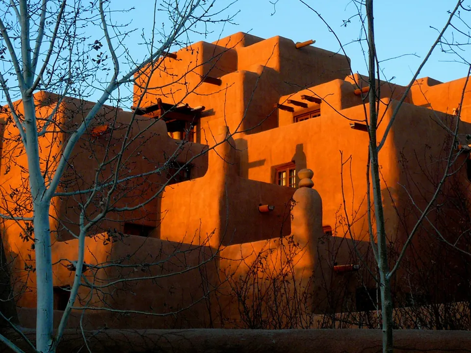 An orange adobe-style building with wooden beams at sunset