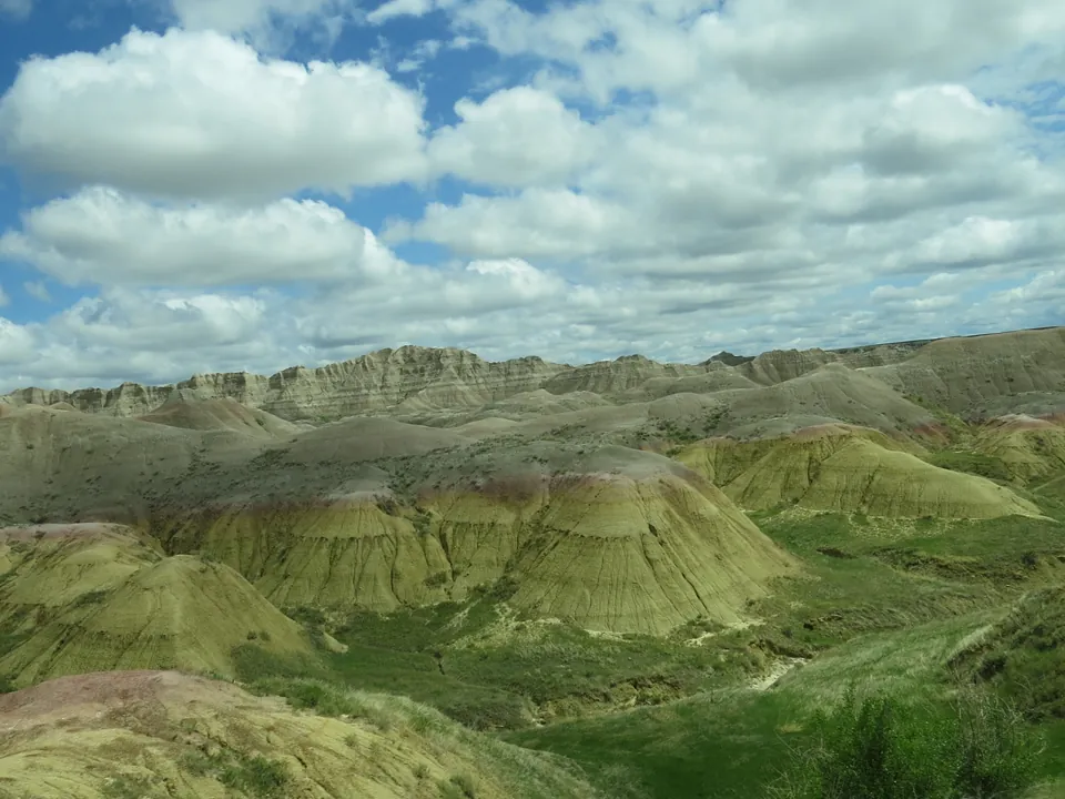 Striped badlands hills and grassland under a blue sky