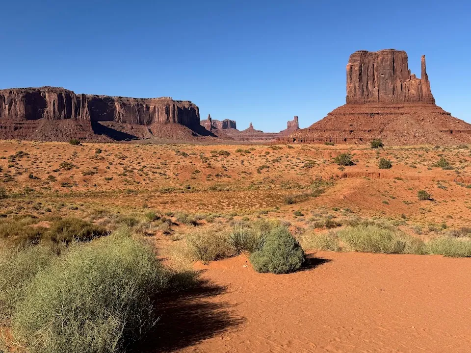 Tall red rock buttes rising from a sandy desert