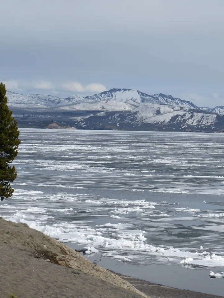 A cold lake with waves and snowy mountains
