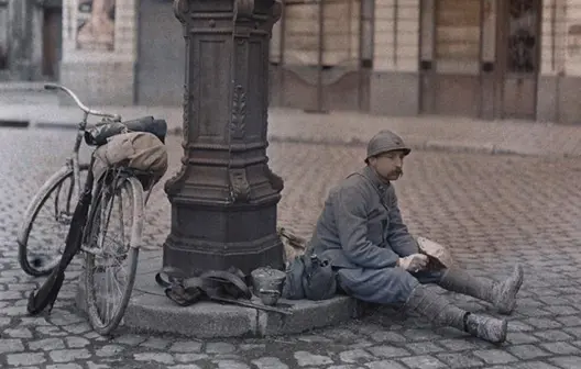 World War I soldier resting beside a lamppost with his bicycle and gear on a cobblestone street