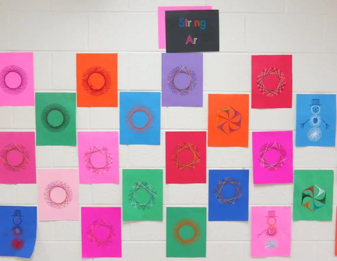 Fourth grade string art bulletin board showing snowflakes and snowmen